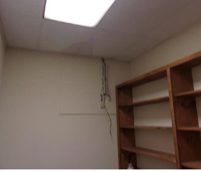Office with wood bookshelves and water stains on the ceiling tile