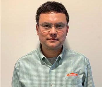 Bust photo of middle-aged male with glasses wearing SERVPRO button-down shirt, standing in front of white background