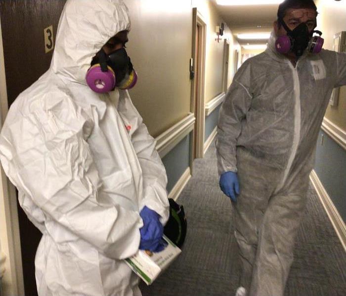 technicians in PPE in a hallway